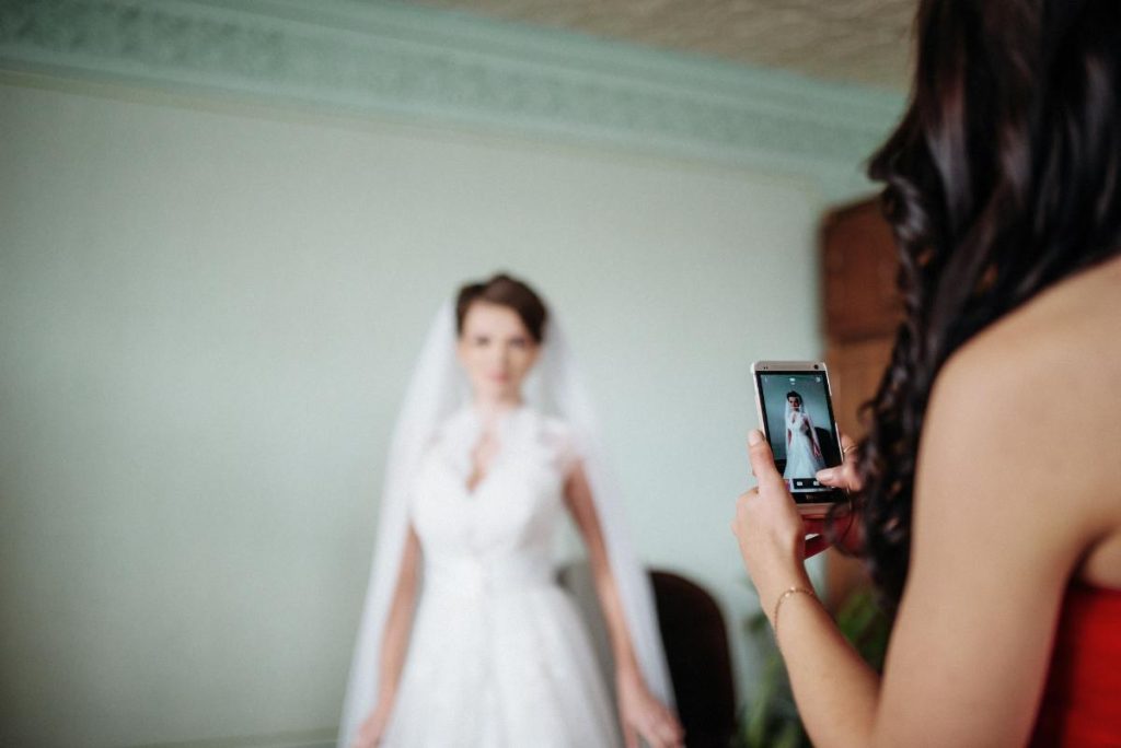 bridesmaid taking picture of bride with phone