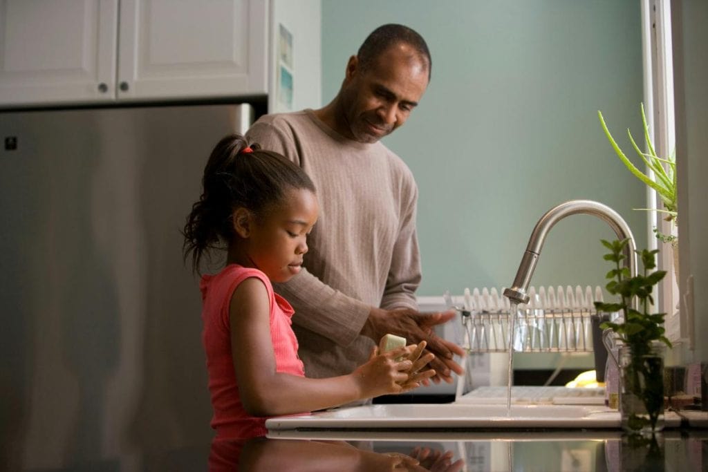 father and daughter washing hands at sink