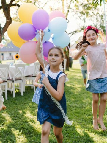 girls running with balloons at a birthday party