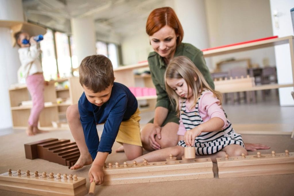 teacher watching children play with wooden toys