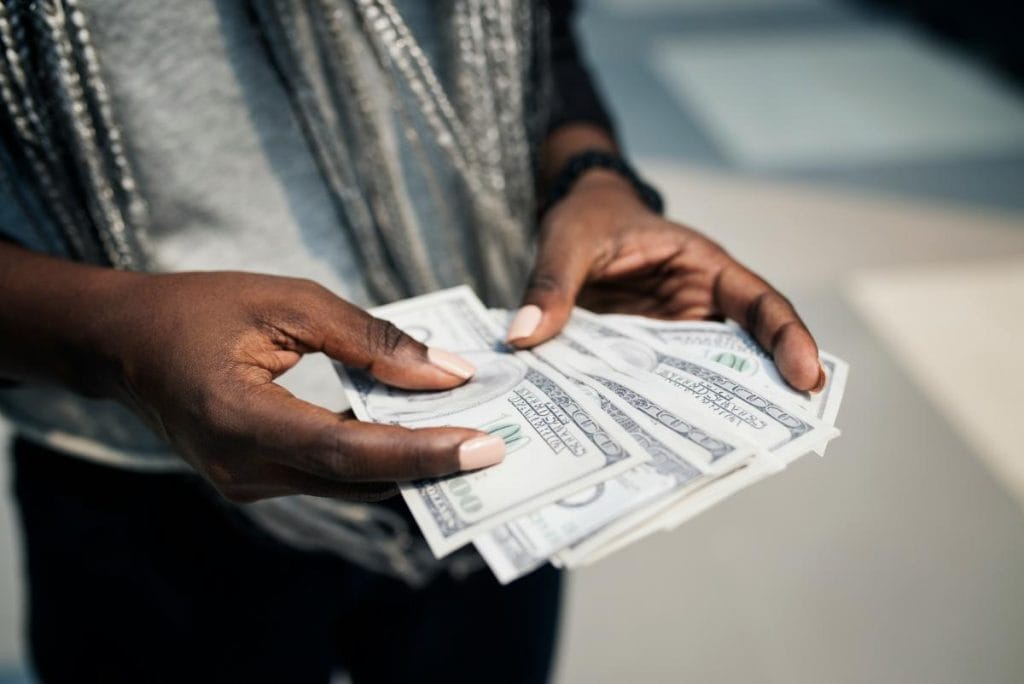 hands holding cash in the form of hundred dollar bills