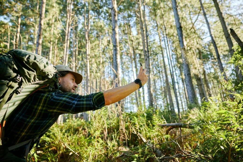 man with backpack and phone in the wilderness