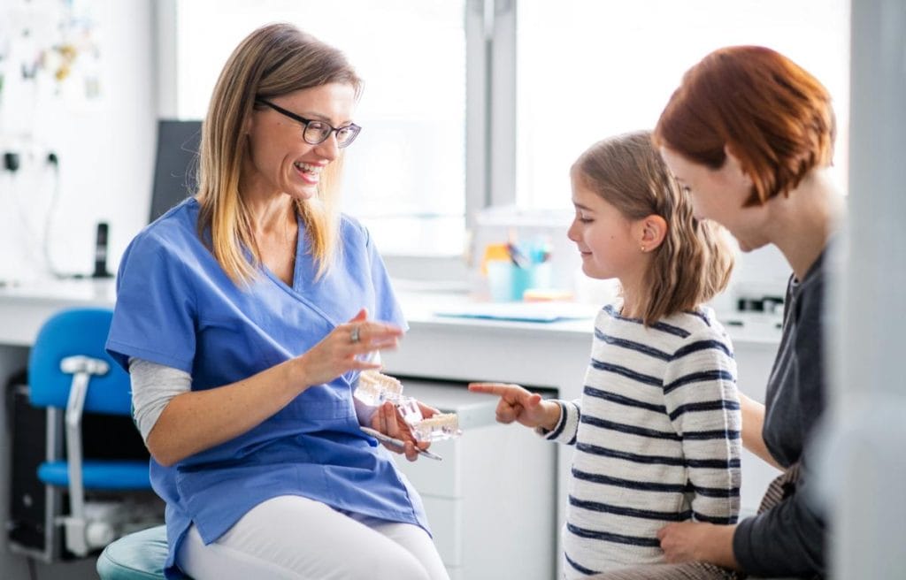 mother and daughter talking to dentist