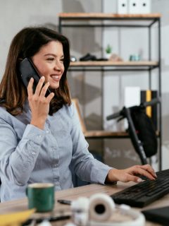 woman talking on phone and using desktop computer