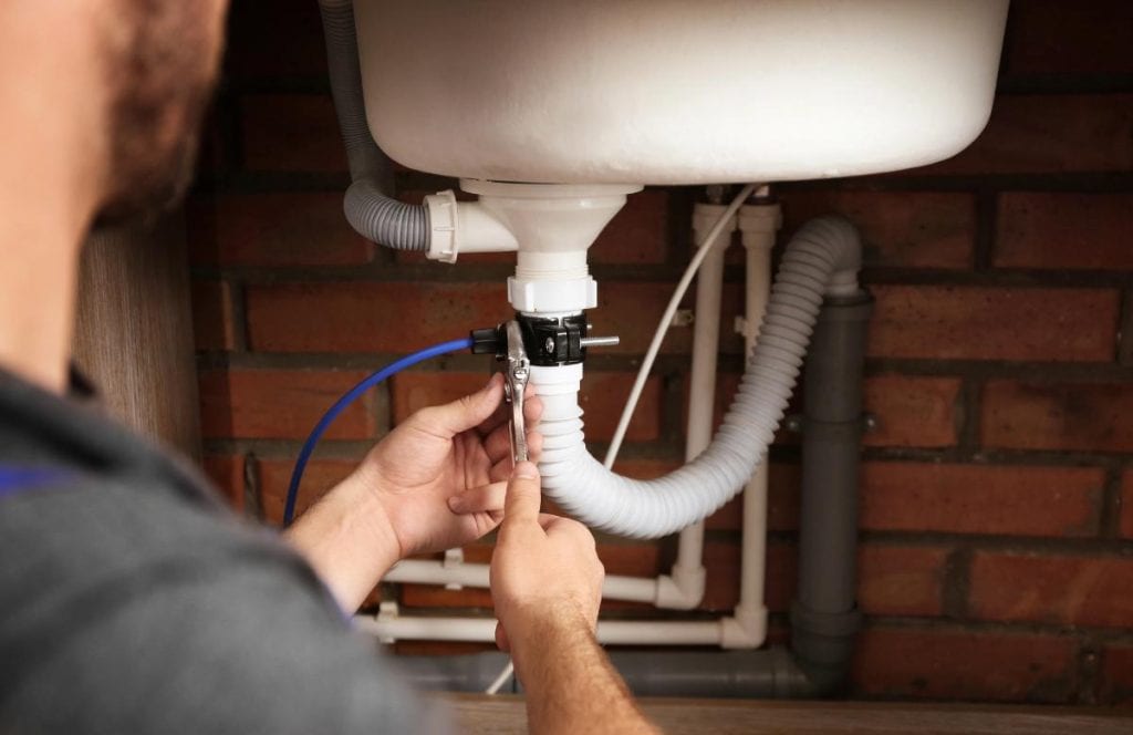 plumber looking at pipes under sink