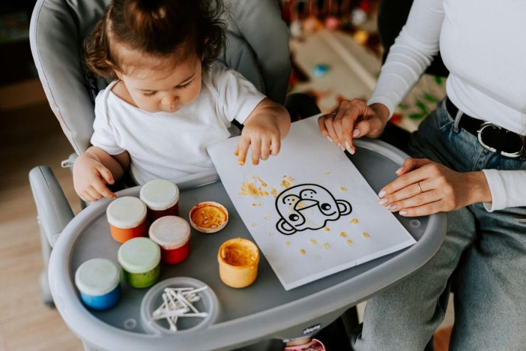 woman watching toddler finger painting