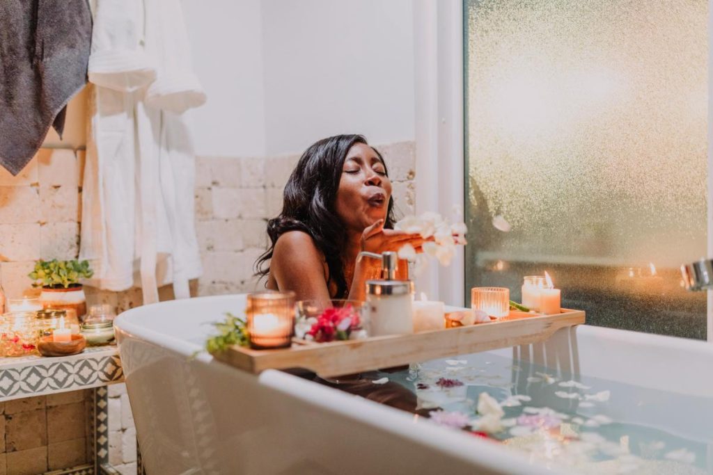 woman in a bubble bath surrounded by flower petals and candles