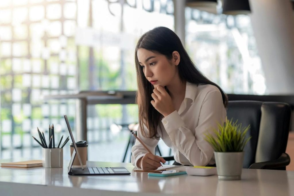 woman taking notes and using tablet