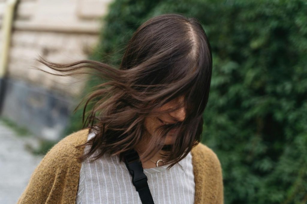 woman with short hair walking outdoors, wind blowing through hair