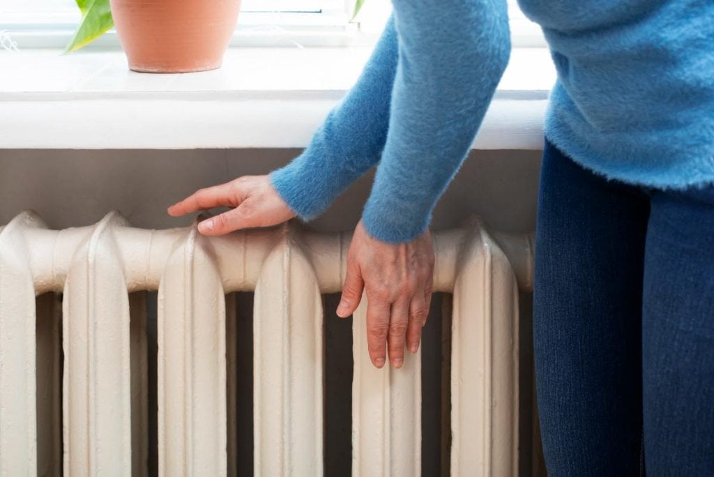 woman warming her hands near the radiator