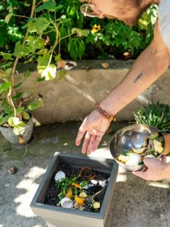 person putting food scraps in garden soil as fertilizer