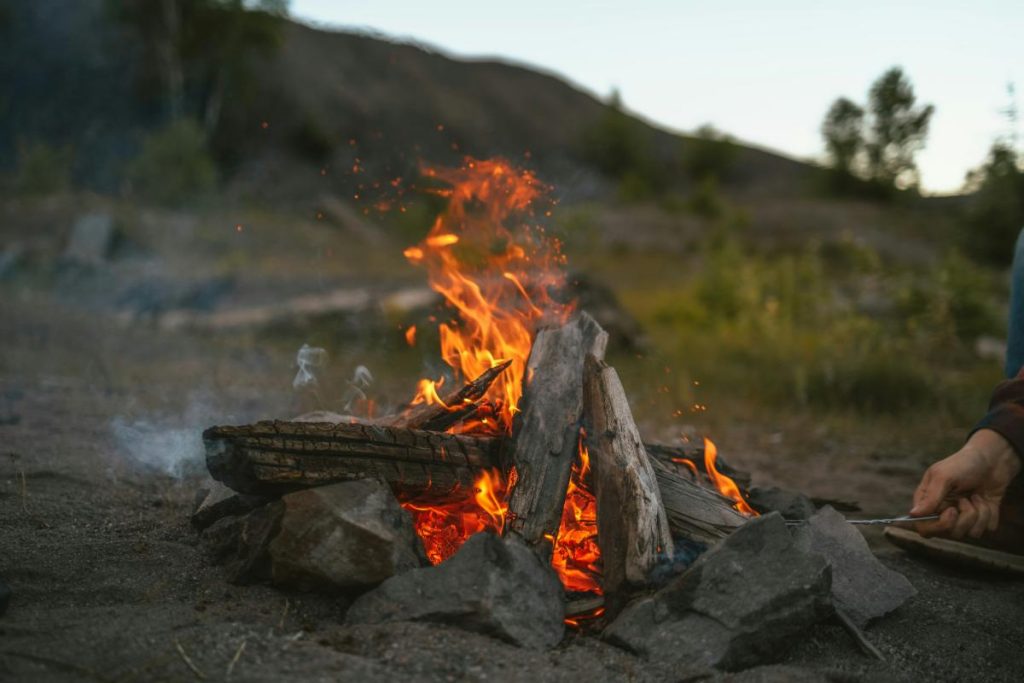 person stoking a campfire