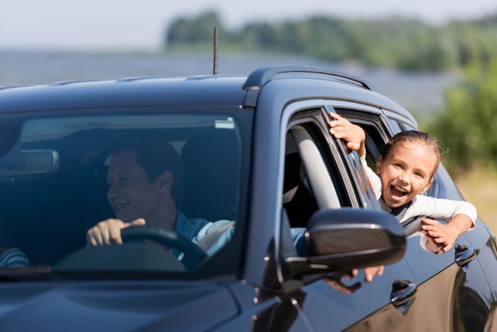 family in rental car with happy girl looking through window
