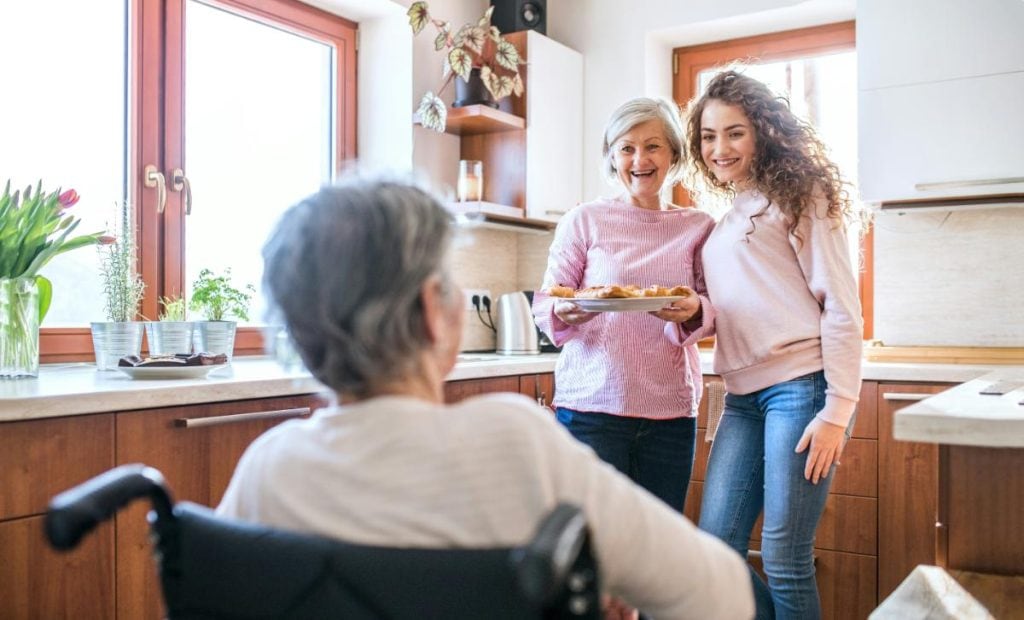 grandmother in wheelchair with adult daughter and granddaughter in kitchen