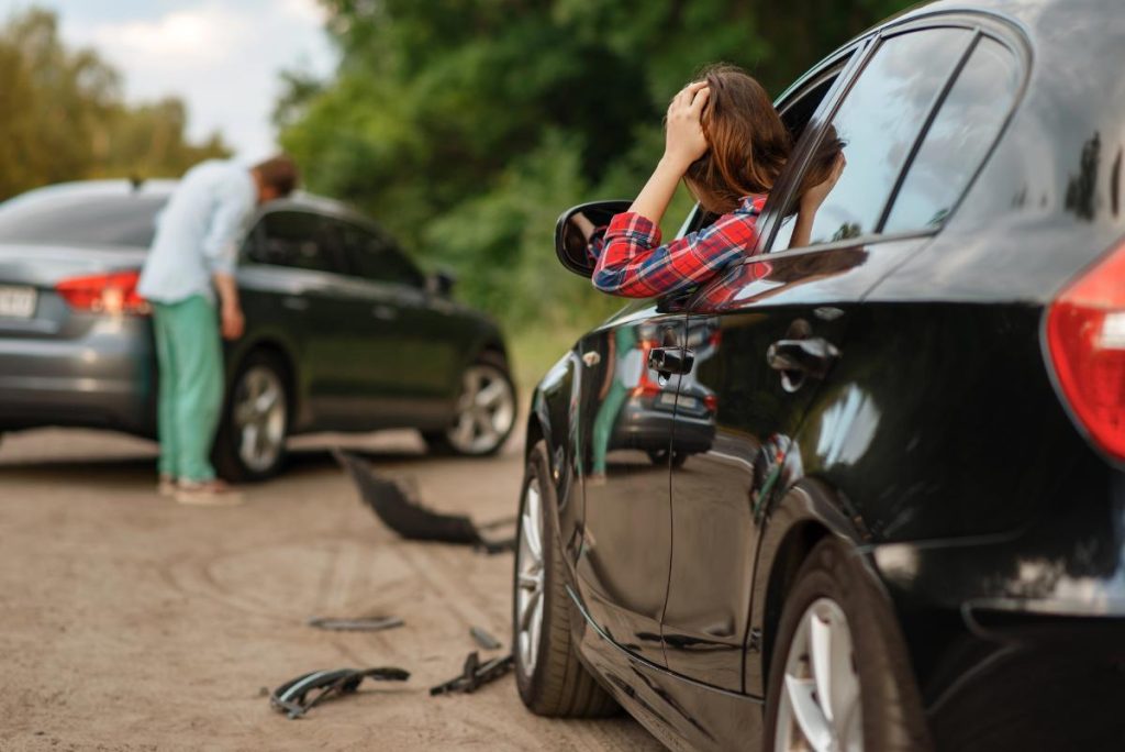woman and man separate cars after a car accident with debris on the road