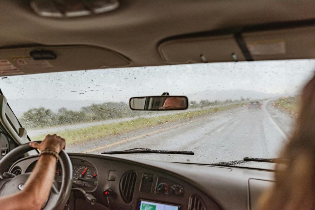 couple driving in the rain - view from windshield looking onto the road ahead