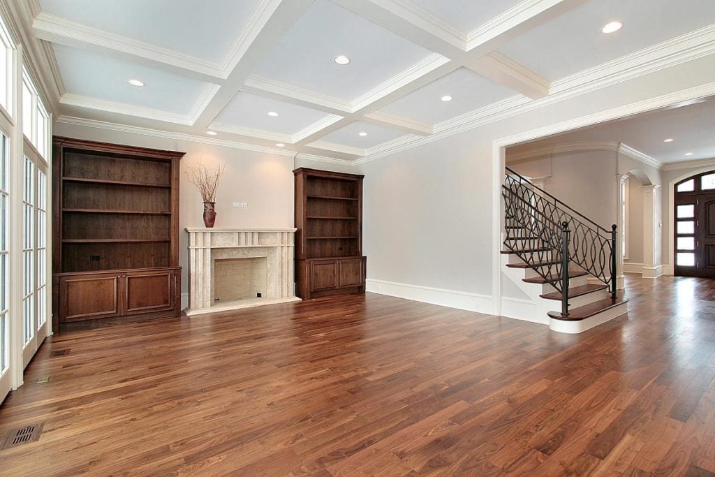 cherry hardwood floors in a large family room with built in bookcases and a fireplace