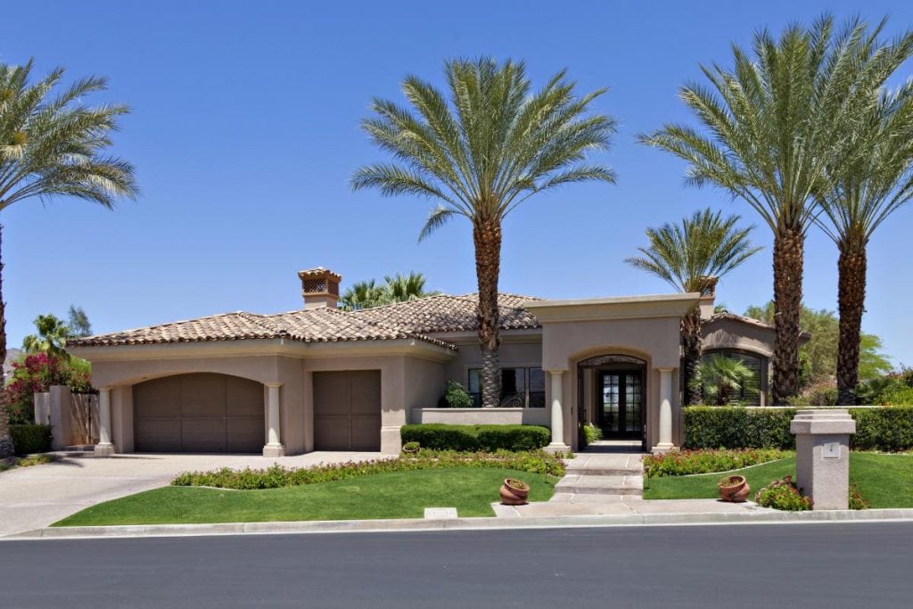 front of large california home with palm trees