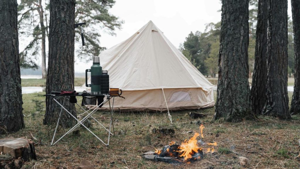 large white tent set up a campground with a campfire nearby