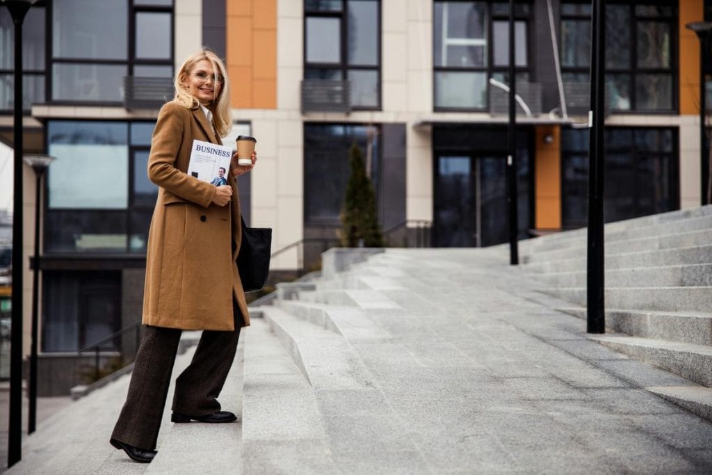 elegant older blonde woman in brown trench coat