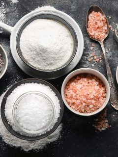 various types of salt in small bowls on black background