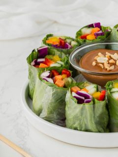 veggie and lettuce wraps on white plate with peanut sauce