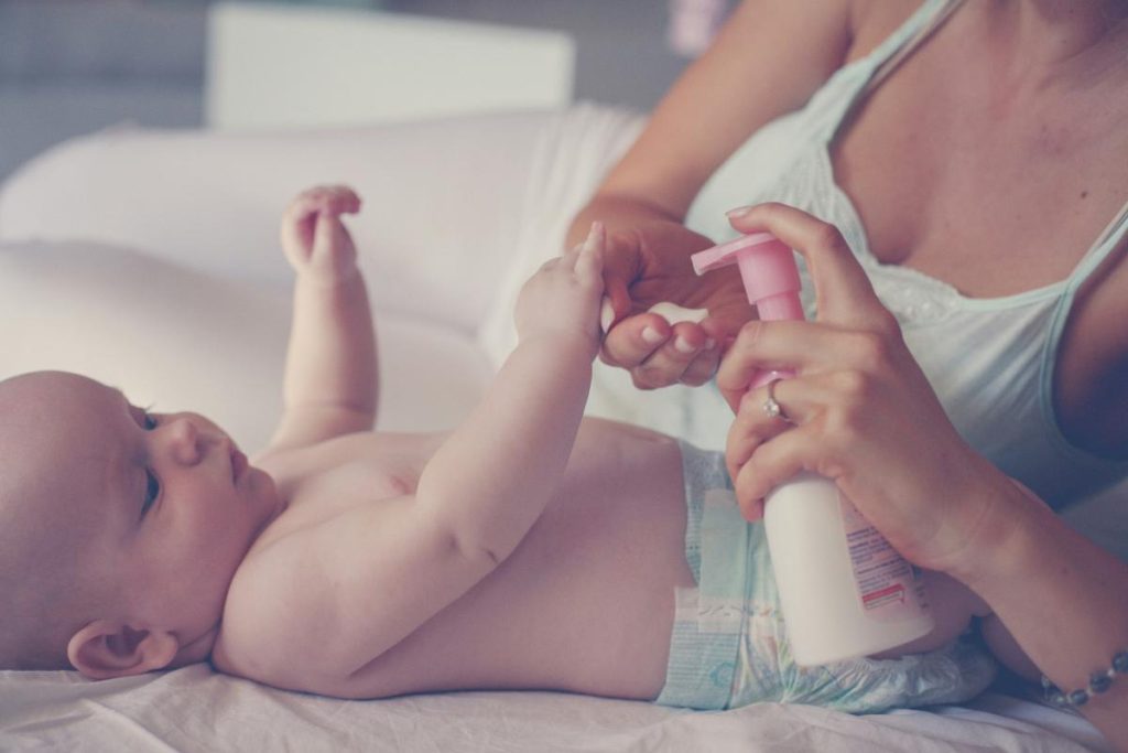 mother applying lotion to baby's skin
