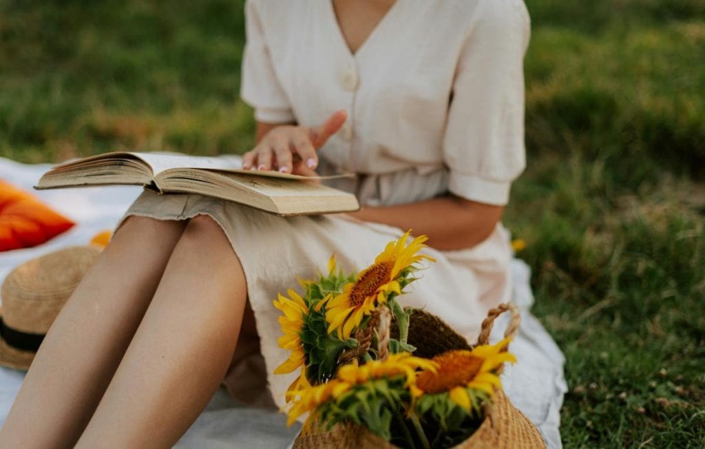 woman with a book on a blanket outdoors