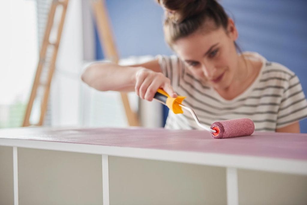 brunette woman repainting bookshelf