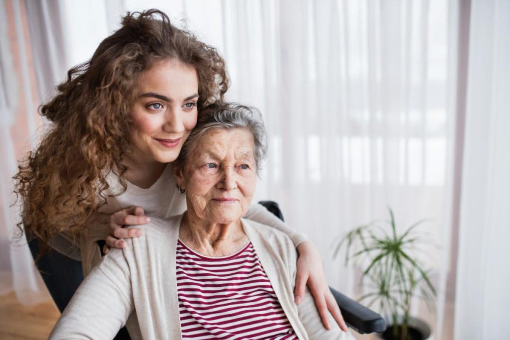granddaughter embracing grandmother from behind wheelchair