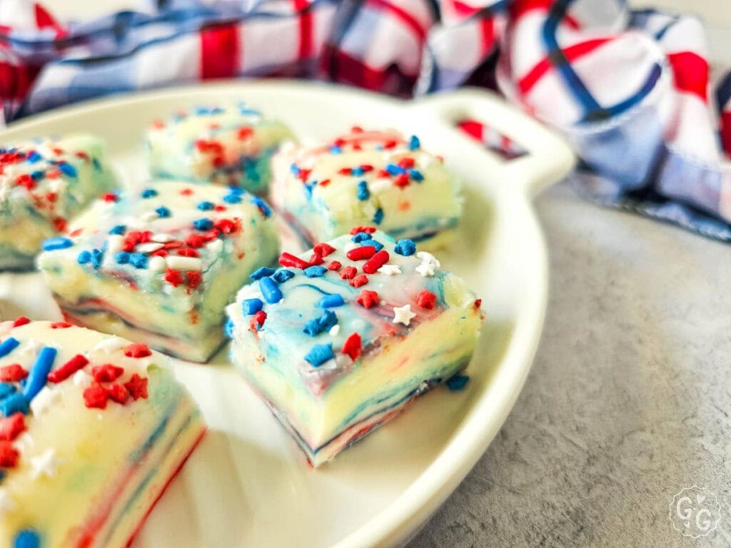 Festive white chocolate fudge with red and blue swirls and colorful sprinkles, arranged in a round dish, ideal no-bake treat for Independence Day celebrations.