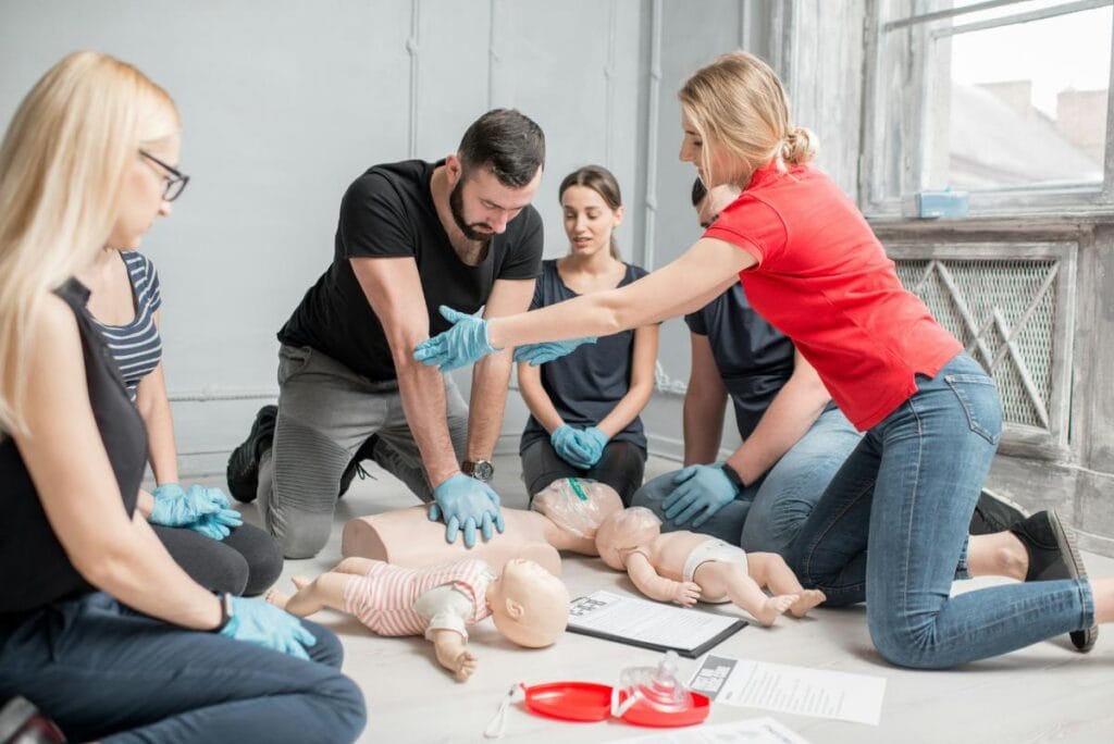 Adults practice CPR on training mannequins during a hands-on safety training seminar.