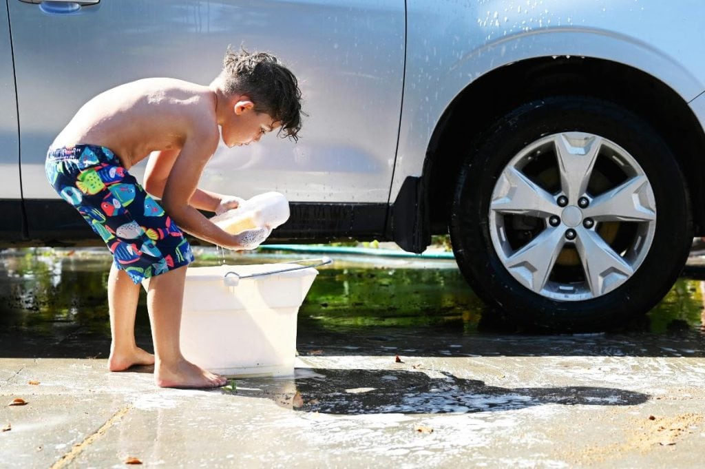 little boy washing the car for his parents in the summer