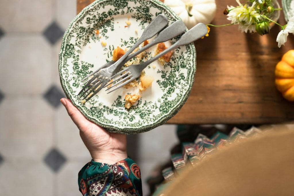 A decorative plate with leftover crumbs and used forks—hidden food debris like this can attract ants and cockroaches in the home.