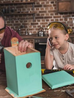 a father and daughter building a teal birdhouse