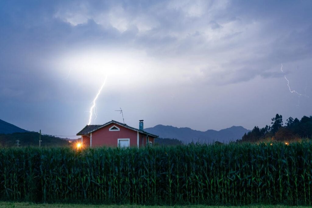 lightning over a house in a rural area
