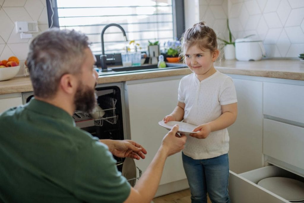 little girl helping dad unload and put away the dishes