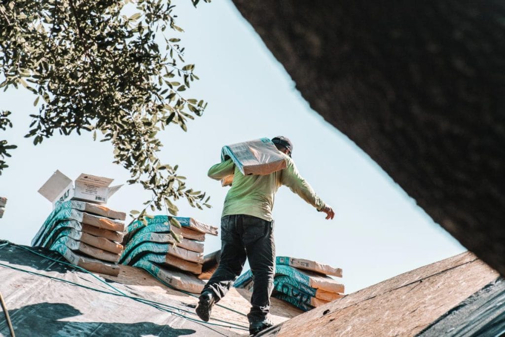 man carrying materials on roof to make roof repairs
