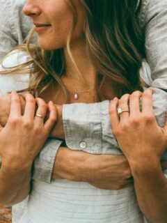 unidentified man embracing woman around the shoulders from behind