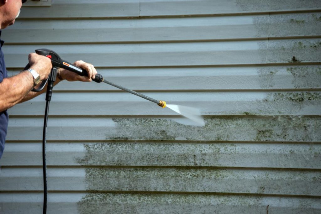 man power washing the siding