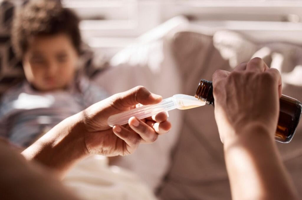 mom using a medicine measuring spoon to give child medicine
