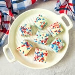 Top-down view of red, white, and blue layered fudge with sprinkles, styled with a plaid napkin for a fun and easy patriotic dessert.