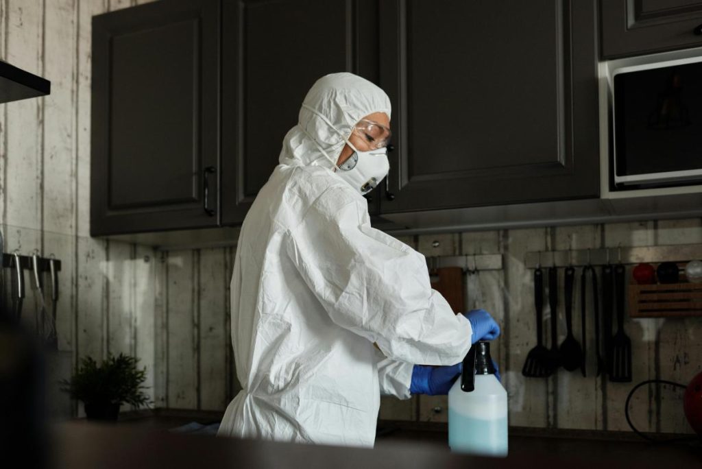 person using a spray to sanitize a kitchen to keep pests away