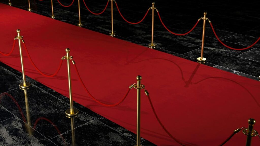 Luxurious red carpet lined with gold stanchions and red velvet ropes, creating a VIP entrance for parties and special occasions.