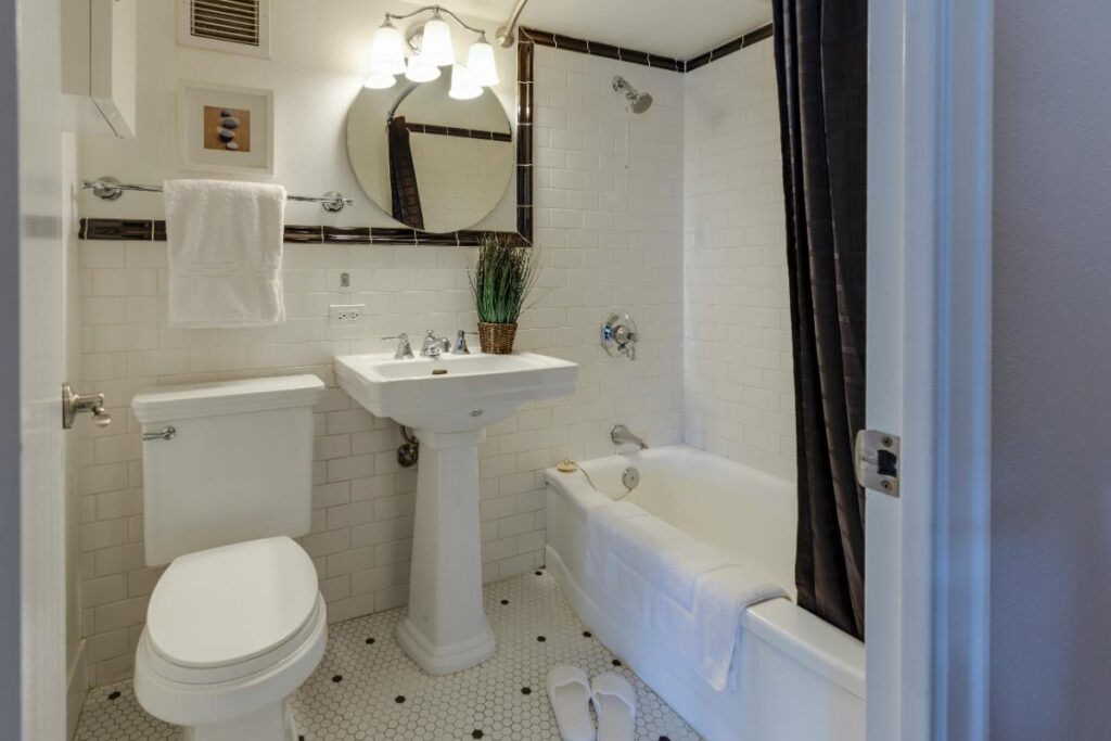 Compact bathroom featuring white subway tile, pedestal sink, and efficient layout—an example of smart renovations for small residential spaces.