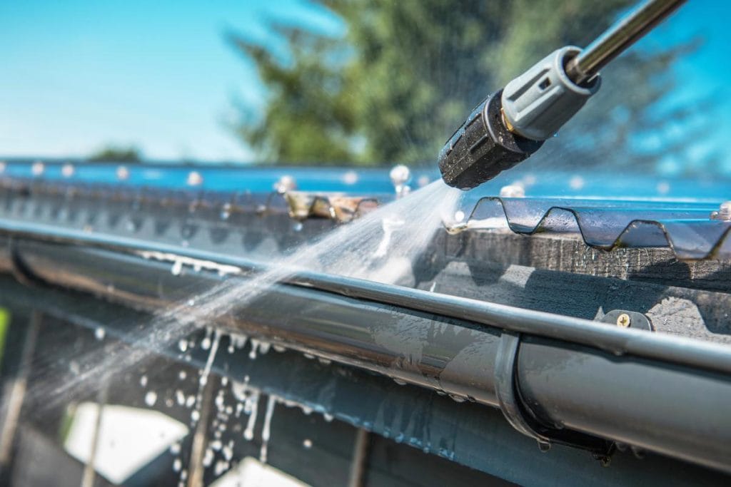 spring cleaning the gutters using a power washer