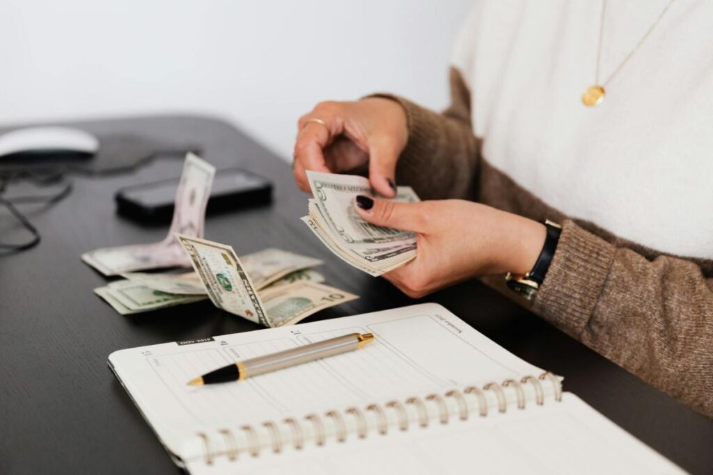 a woman at a desk with a notebook counting money
