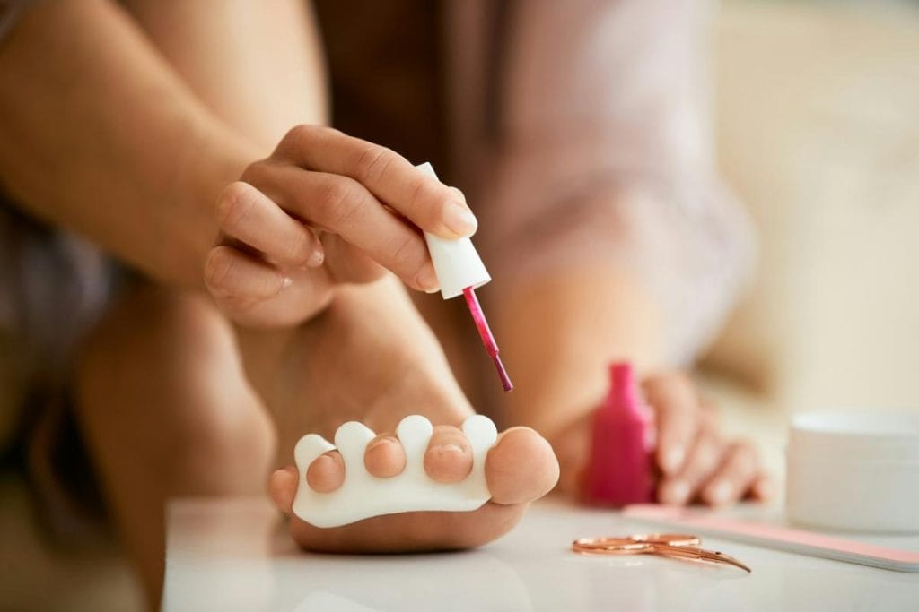 woman painting her toenails dark pink