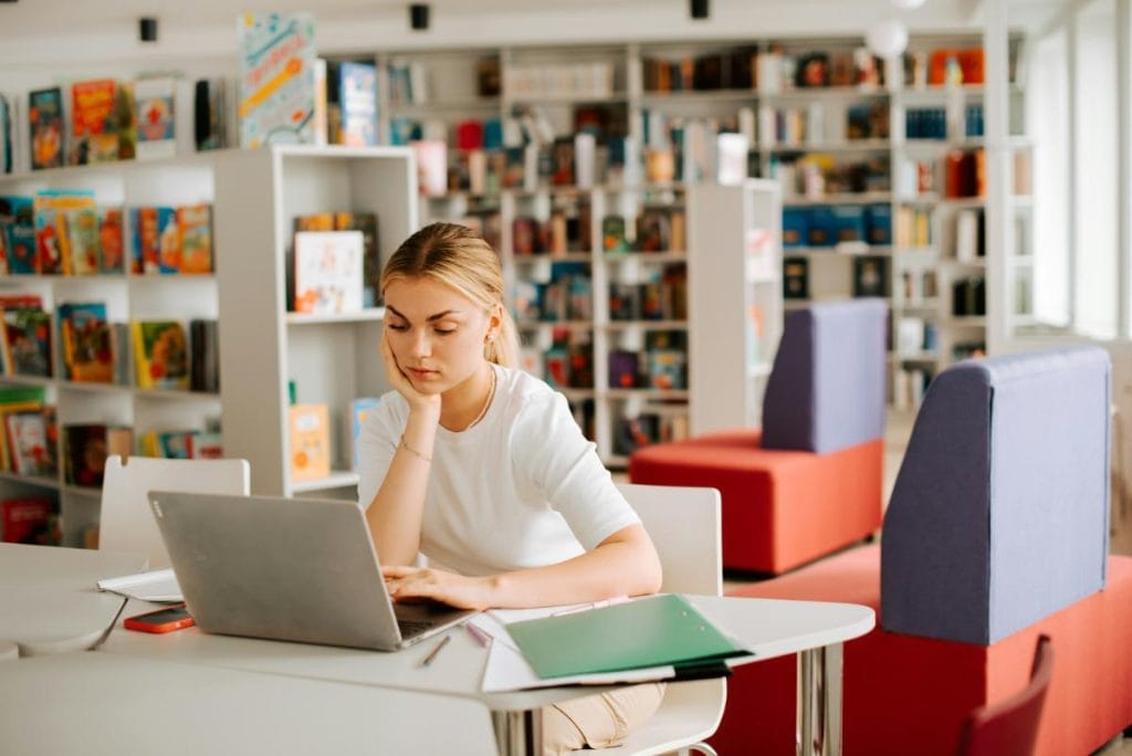 young blonde woman studying in a library