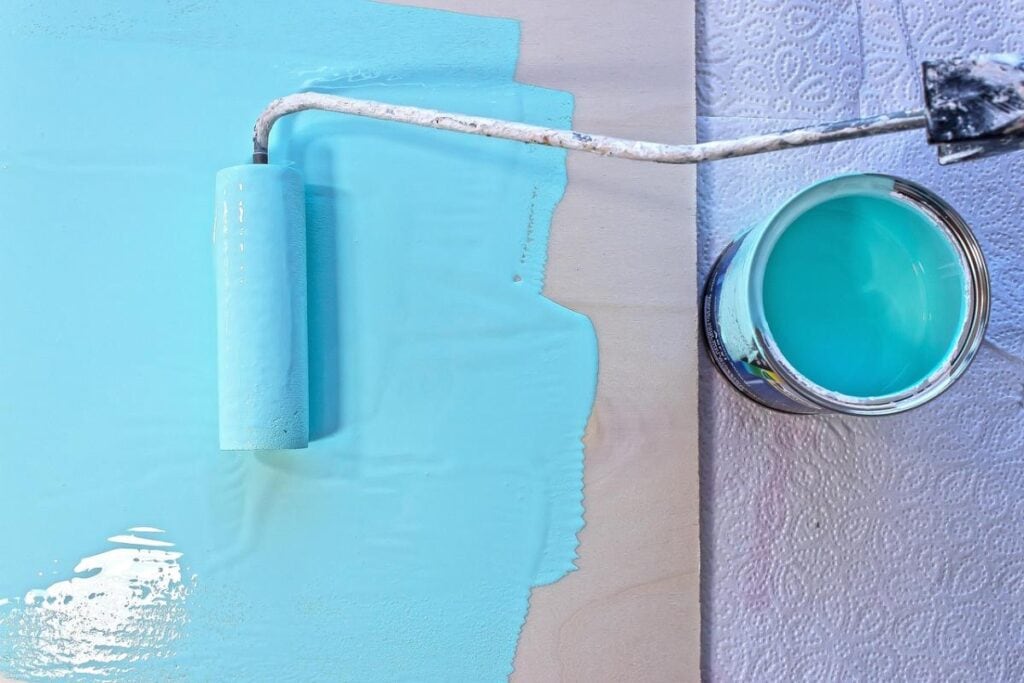 blue paint being rolled onto a white surface